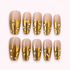 Mansa Musa gold chrome rhinestone press-on nails on a pale pink background